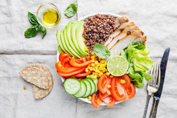 Healthy salad bowl with quinoa, tomato turkey, avocado, sweet pepper, corn, lime and mixed greens, top view. Healthy food conception. Superfood meal.