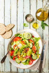 Healthy vegetable salad of fresh tomato, cucumber, lettuce and corn on plate, top view. Diet menu.