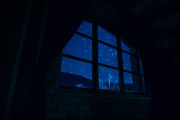 Night scene of stars seen through the window from dark room. Night sky inside dark room.