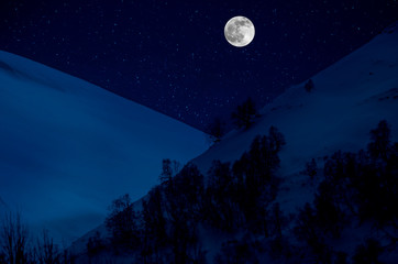 Naklejka na ściany i meble Majestic winter night in a mountain valley with full moon in a starry sky.