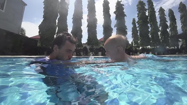 Happy smiling toddler is diving under water with father