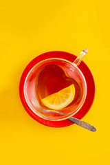 Cup black tea heart shaped cup and red saucer, top view on yellow background