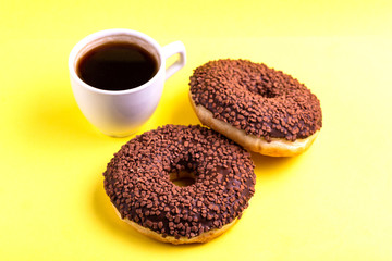 Two delicious chocolate donuts with sprinkle and cup of coffee