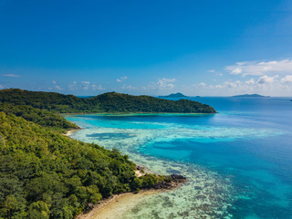 Fototapeta premium Aerial view of tropical beach of island Bulalacao. Beautiful tropical island with white sandy beach, palm trees and green hills. Travel tropical concept. Palawan, Philippines