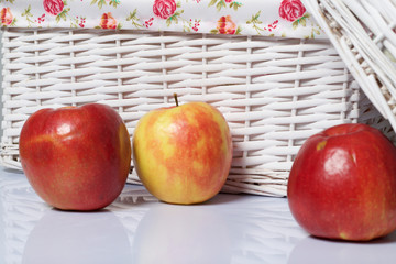 Apples on the table. Next to white wicker baskets.