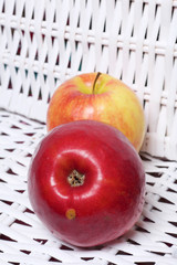 Juicy delicious apples. Lies on a white wicker basket.