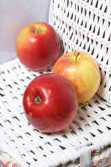 Juicy delicious apples. Lies on a white wicker basket.