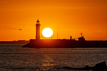 Orange sunset next to lighthouse.