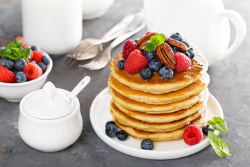 Stack of fluffy pancakes with fresh berries and pecan nuts