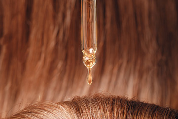 Close-up drop of oil restore and recovery hair is applied to head bulbs. Concept hairdresser spa...