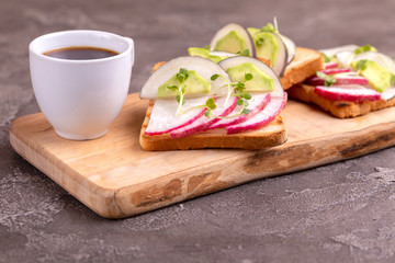 Tasty toasts with radish, avocado and sprouts, cup of coffee