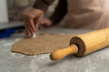 close up of a rolling pin and hands who are cutting out cookies of the biscuit dough