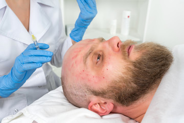 Obraz na płótnie Canvas The doctor cosmetologist makes the Rejuvenating facial injections procedure for tightening and smoothing wrinkles on the face skin of a men in a beauty salon.Cosmetology skin care.