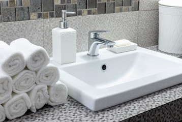Fototapeta premium Stack of clean white towels on ceramic countertop in bathroom