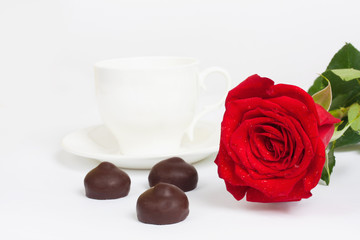 Beautiful red rose and cup of hot tea with chocolate
