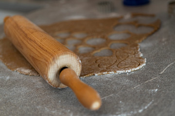 Fototapeta na wymiar close up of a rolling pin and a biscuit dough with cutted out cookies