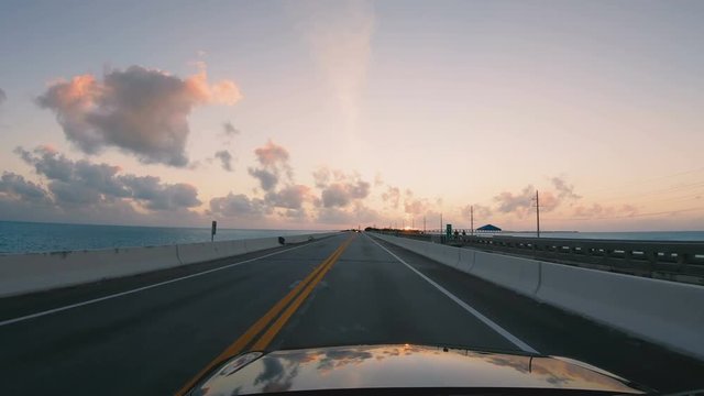 Driving a car along Florida Keys Overseas Highway bridges during sunset. POV