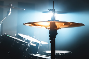 Close-up Drum set in a dark room against the backdrop of the spotlight. Atmospheric background symbol of playing rock or jazz drums. Copper plates on a cold background