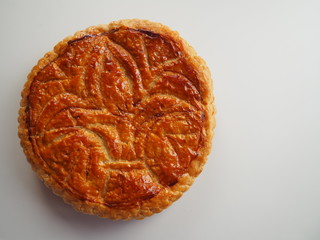 Homemade Epiphany cake or Twelfth Night cake (french galette des rois) made of puff pastry and frangipane (almond cream), white background