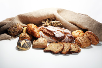 Different kinds of bread and bread rolls on board from above.