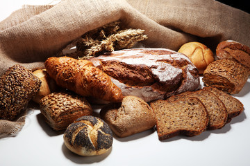 Different kinds of bread and bread rolls on board from above.