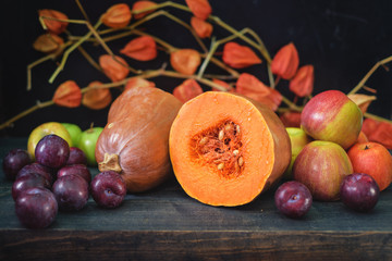 Rustic autumn still life with pumpkins and golden leaves on a wooden surface.