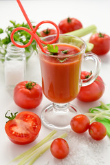 Fresh tomato juice. Tomato juice in glass with celery, cherry tomato, white wood background, closeup