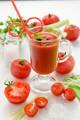 The most useful juice. Tomato juice from fresh tomatoes. Tomato juice in glass with celery, cherry tomato, white wood background, closeup