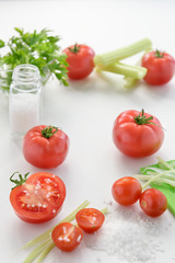 The most useful juice. Tomato juice from fresh tomatoes. Tomato juice in glass with celery, cherry tomato, white wood background, closeup