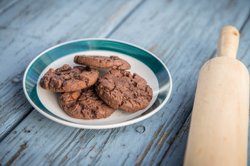 A plate of cookies on and a rolling pin on a blue wooden floor