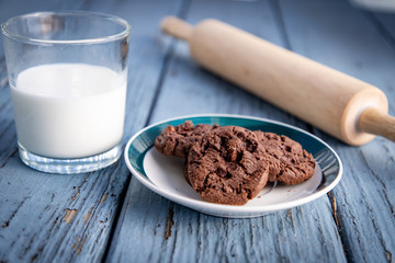 A plate of cookies, a glass of milk and a rolling pin on a wooden floor