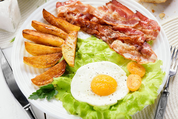 Morning breakfast with delicious fried bacon. French fries and tender egg, close-up.