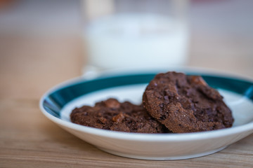 Close up of a plate of cookies with a glass of milk on the background