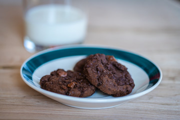 Close up of a plate of cookies with a glass of milk on the background
