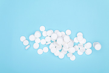 White pills on blue background.Background of large white tablets on blue paper. Pile of pills.