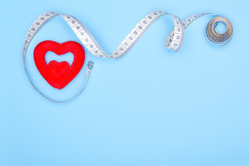 Сoncept of a cure for the heart.Heart, flexible ruler on a blue background as a concept for losing weight and healthy lifestyle.