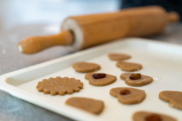 rolling pin and cutted out raw cookies in a baking plate
