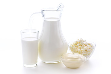 Fresh cow milk in a glass on a white background with a useful curd and sour cream on a white background. Delicious dairy products.
