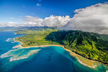 Aerial view of Na Pali Coast, Hawaii, taken from a helicopter with high white clouds over green...