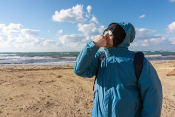 Hooded men in sunglasses standing on the sandy beach near rescue booth thinking and looking to the ocean coast and sun