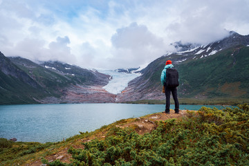 Girl tourist looks at a glacier. Svartisen Glacier in Norway.