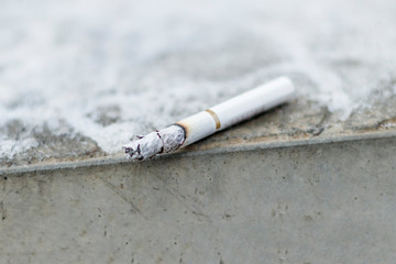 shallow depth of field. cigarette smoldering lies on the concrete step