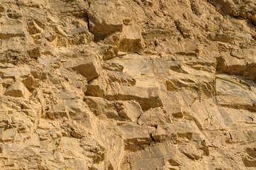 Surface of the rock with a granite stone texture. Designer background for interiors. Stone surface of a yellow texture close-up.