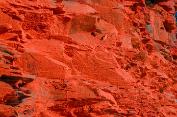 Surface with a texture of red stone. Designer background for interiors. Stone surface of a red rock.