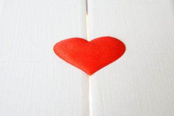 Red heart on a white wooden surface and glowing lines. Health problems and cardiology