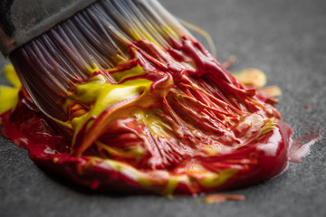 Paintbrush mixing red and yellow colors extreme macro close-up