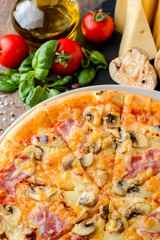 Italian pizza and ingredients on a wooden background, top view