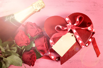 Happy Valentine's Day red heart shape gift box of chocolates gift on vintage style pink wood table background with lens flare.