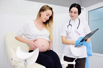 young pretty pregnant woman in a clinic at a female consultation with a gynecologist-obstetrician doctor