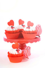 Red and white Valentine's cupcakes with hearts and love bug decorations with lens flare.